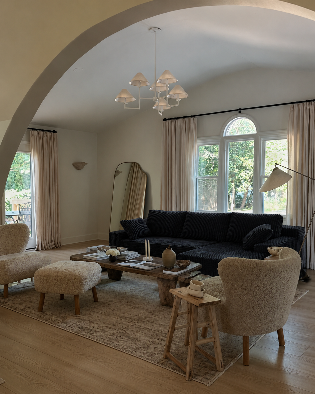 Black L-shaped couch with a round wood coffee table and light accent seating